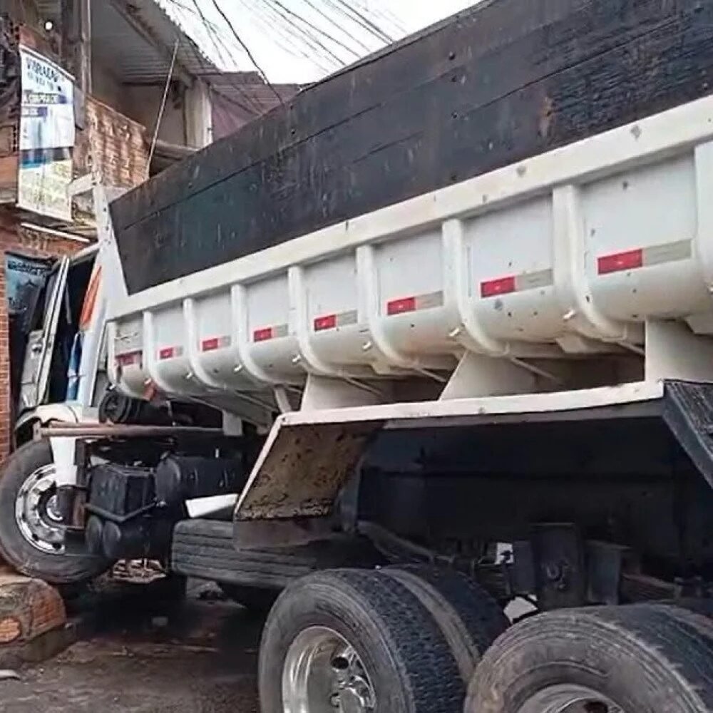 Caminhão caçamba branco e preto batido contra a fachada de um comércio no bairro Paulo VI