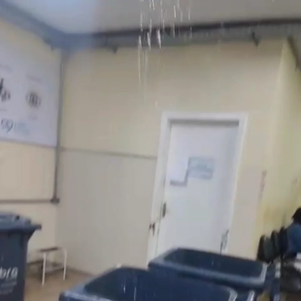 Corredor de hospital afetado por vazamento durante chuva.