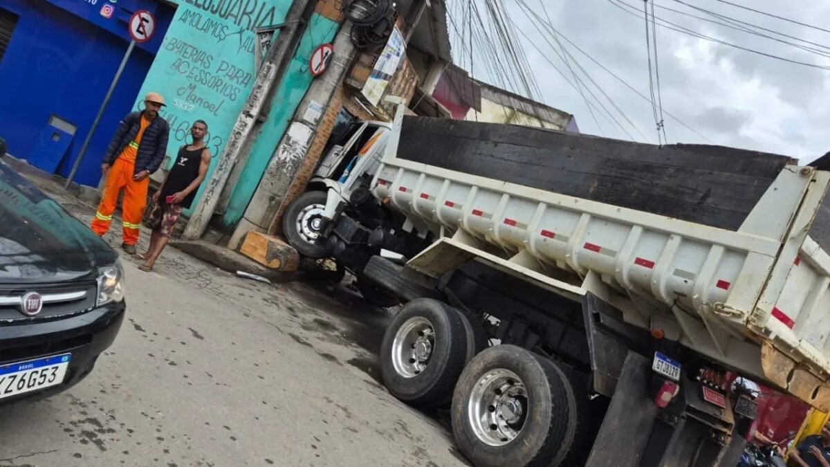 Caminhão caçamba atinge fachada de loja em rua inclinada em BH enquanto homens observam
