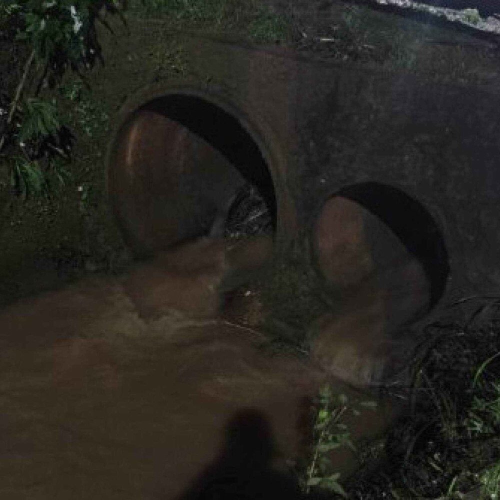 Dois grandes dutos de concreto escuros com água barrenta correndo por eles à noite