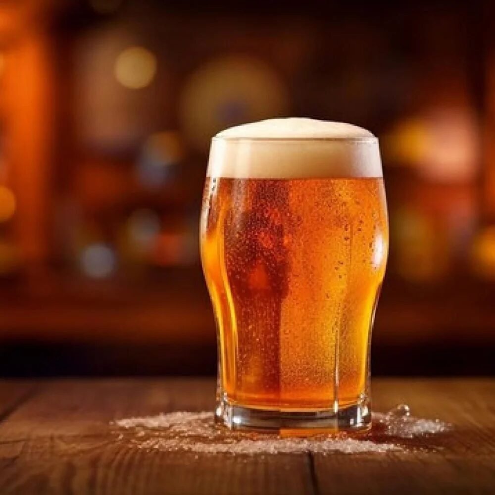 Copo de vidro com cerveja gelada e espuma em cima apoiado sobre uma mesa de madeira